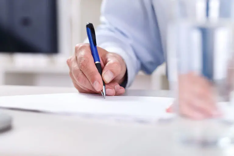 man writing something on paper at a desk