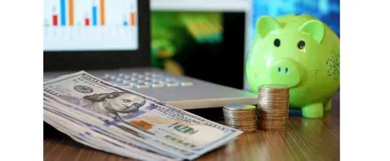 piggy bank and money in front of a computer