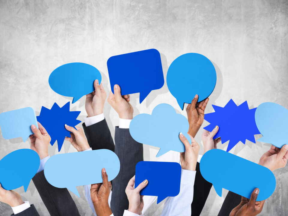 Business arms raised with speech bubble by concrete wall.